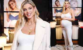 Pregnant Ashley James cradles her growing baby bump in a white jumpsuit