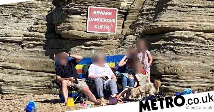 Family sunbathe in front of huge ‘dangerous cliff’ warning sign where child died