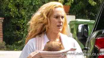 Rumer Willis is every inch the doting mother as she cradles baby daughter Louetta while on a dog walk
