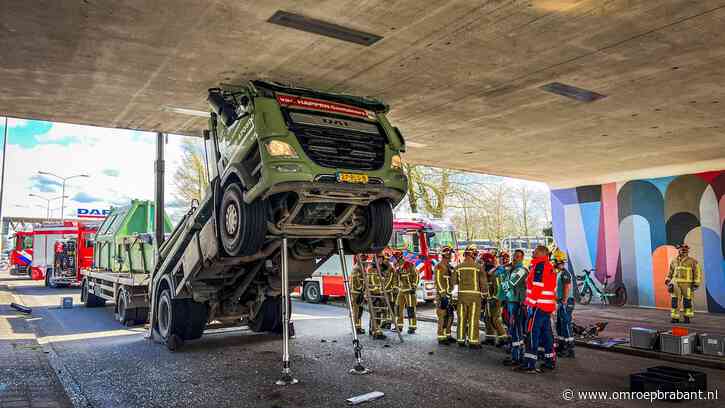 Vrachtauto klem onder viaduct: chauffeur bekneld