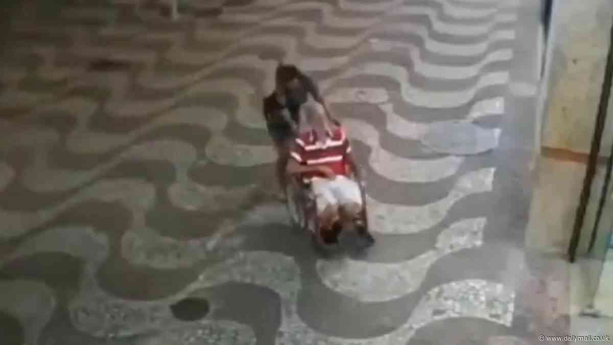 Eerie new footage shows woman struggling to push wheelchair-bound man through streets just one day before she wheeled his dead body into bank to sign off a loan