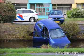 Voertuig hangt met voorkant in water bij Veendam