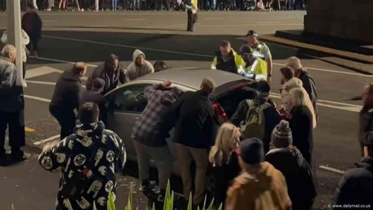 Anzac Day New Plymouth, New Zealand: Moment dawn service attendees join forces to lift and move a car with their bare hands so the memorial could begin
