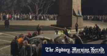 Crowd lifts car out of the way of Anzac ceremony