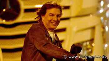 Arc De Triumph! Tom Cruise flashes a broad smile as he rides a motorbike in Paris during Mission Impossible 8 filming