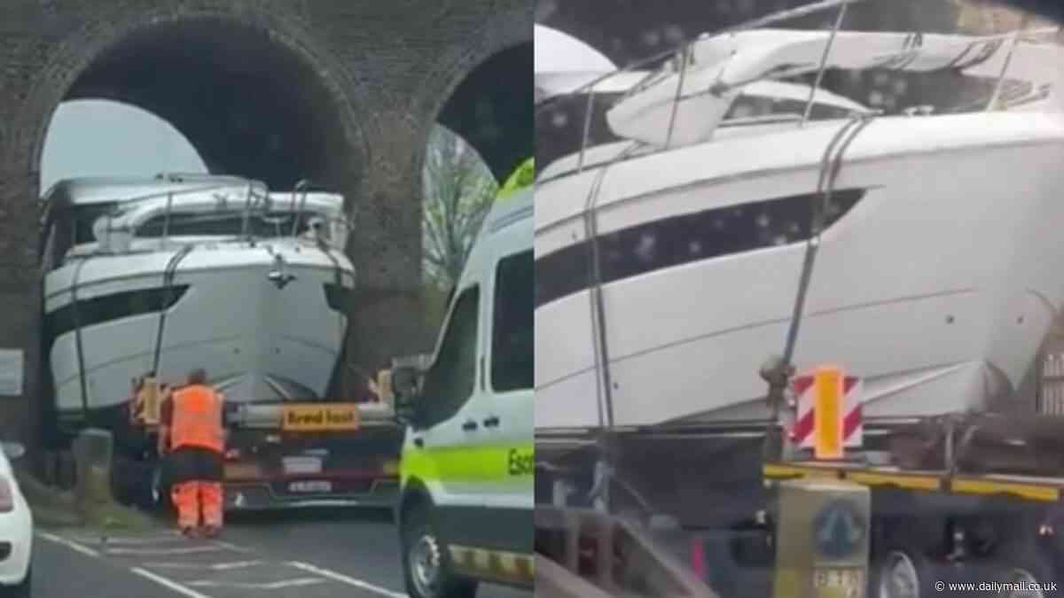 Bizarre moment yacht gets wedged underneath railway arches while being carried on a low-loader