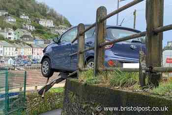 Car left dangling over steep drop after crashing through railings in seaside town