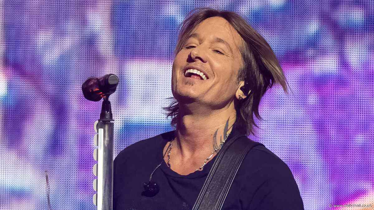 Keith Urban shows off his bulging biceps and rockstar tattoos in a tight black T-shirt as he performs at 2024 iHeartCountry Festival