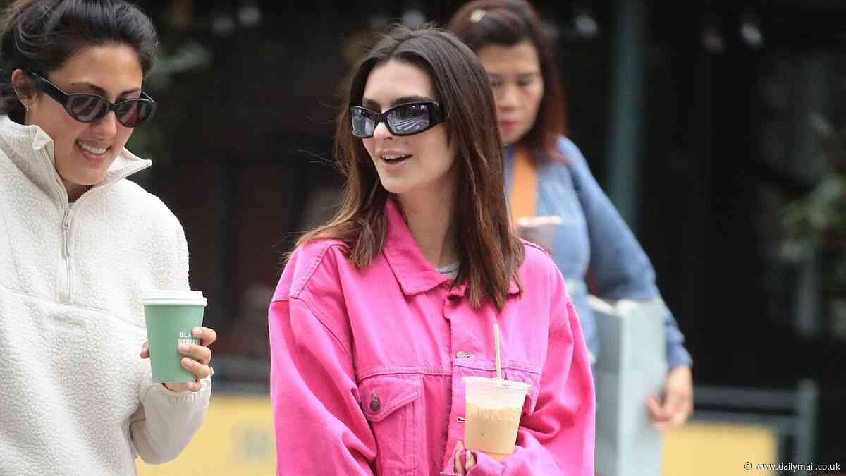 Emily Ratajkowski is pretty in a bright pink denim jacket as she walks her dog Colombo in NYC while picking up an iced coffee