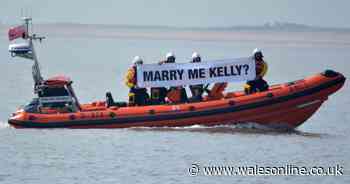 RNLI volunteer surprises partner with proposal - with crew holding up banner on waves
