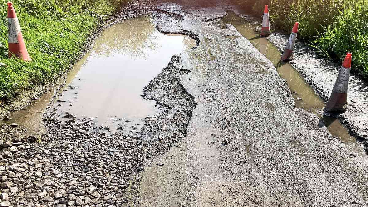 Is this Britain's biggest pothole? Eight-inch deep crater the length of a double-decker bus is blamed for damaging cars and leaving chocolate box village isolated
