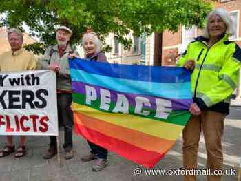 Peace campaigners gather with banners at war memorial