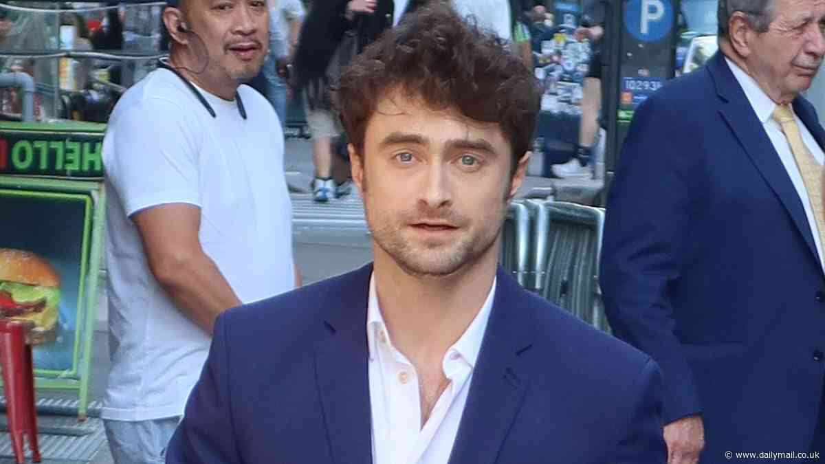 Daniel Radcliffe looks smart in a navy suit as he signs autographs for fans outside The Late Show With Stephen Colbert studio in New York City