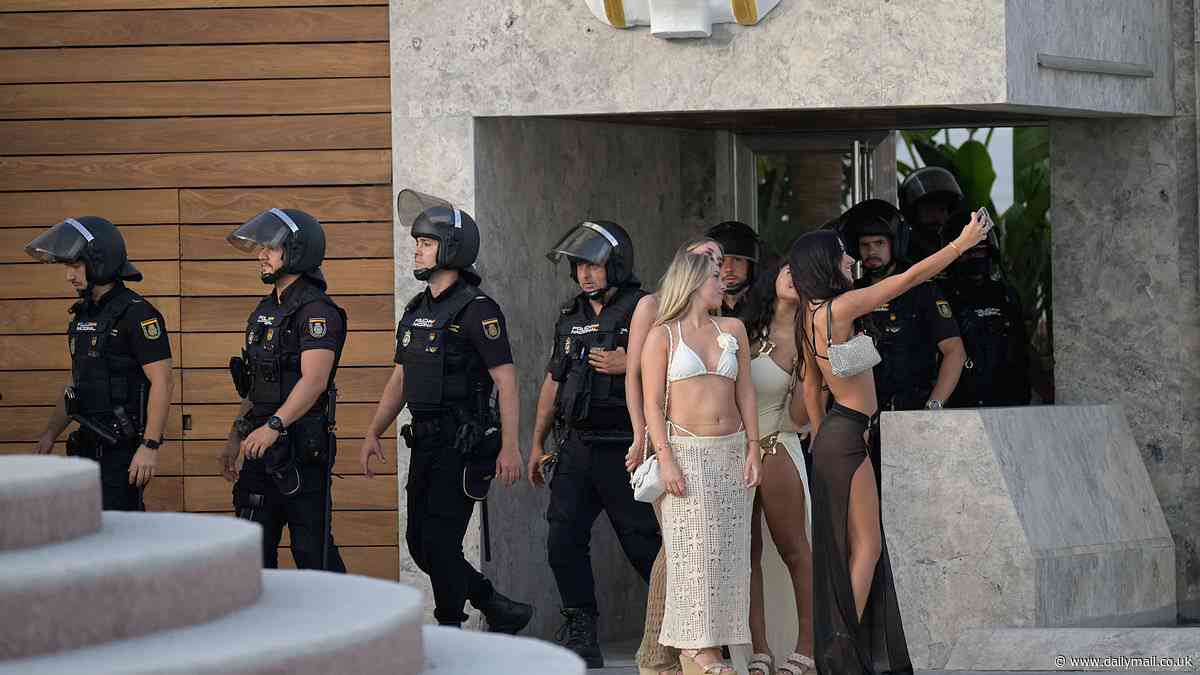 Moment bikini-clad revellers take a selfie as a squad of armoured Spanish cops conduct raid on Marbella beach club where they ordered shocked tourists out of the pool in 'routine check'