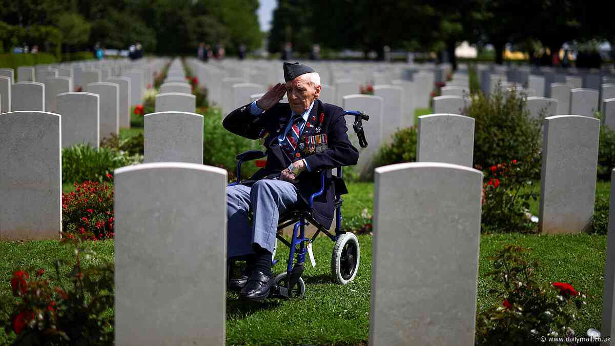 Solitary British D-Day veteran is seen sat in his wheelchair saluting his fallen comrades among their gravestones in moving commemoration picture