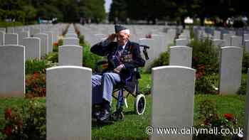 Solitary British D-Day veteran is seen sat in his wheelchair saluting his fallen comrades among their gravestones in moving commemoration picture