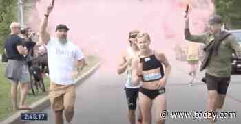 Marathoner reacts after men release confetti, pink smoke around her during final mile