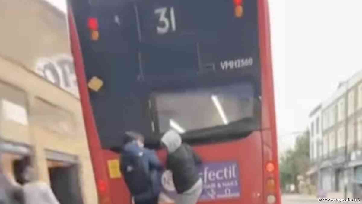 Two 'idiot' youths hang off the back of 19mph London double-decker as they hitch a ride through town