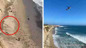 Surfer in Not schreibt Hilferuf mit Felsen in den Sand