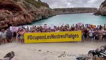 Hundreds of Majorcans take over tiny picture postcard cove made famous by Instagram 'influencers' and unfurl banners reading 'SOS Residents' amid Spanish island's anti-tourism backlash against UK holidaymakers