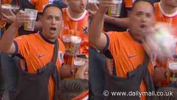 Netherlands fan drops pint of beer after being pelted in the face by a ball while posing for a TV camera during Euro 2024 game against Poland
