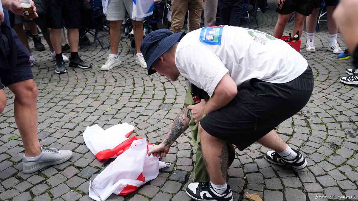 Scottish fans burn the England flag after a day of drinking at Euro 2024 in Germany as the Tartan Army descend on rain-hit Cologne ahead of their match against Switzerland