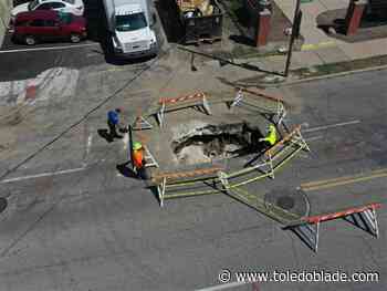 City workers examine 10-foot long sinkhole in downtown Toledo