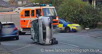 Emergency services descend as car flips on side on quiet residential road