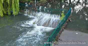 Gushing water runs off surface of water logged Hornchurch car park into river