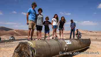 Defiant children play on wrecked rocket in the Israeli desert - as IDF gears up to strike Iran nuclear sites 'within days'