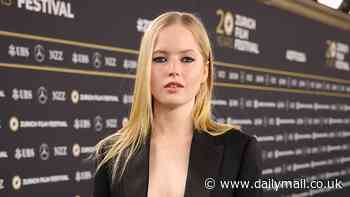 Ellie Bamber goes braless under a very low cut suit as poses on the red carpet at the Zurich Film Festival