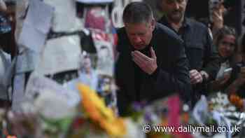 Liam Payne's heartbroken father pauses to kiss pictures of his son at fans' makeshift shrine to One Direction star in Buenos Aires