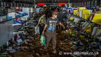 Shocking moment looters raid Valencia store as mobs hit shops and dozens are arrested - while desperate families resort to rummaging through mud to find food in flooded supermarkets