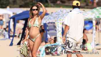 Steph Claire Smith suns herself on Noosa beach and shows off her growing baby bump in peachy bikini