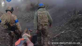 Fearless under fire: Moment Ukrainian soldiers don't even flinch as explosions erupt around them while carrying wounded comrade in new footage showing frontline combat