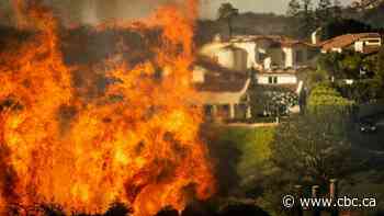 Tens of thousands flee as homes burn and wildfire whips through L.A. hillside