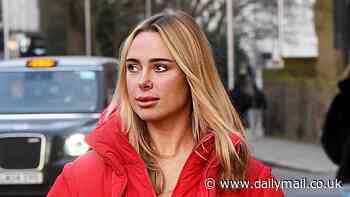 Kimberley Garner puts on a striking display in a bright red padded jacket and matching leggings as she loads tins of paint into the boot of her Ferrari