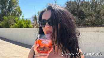 Charli XCX shows off her sizzling figure in a black bikini as she sips on an Aperol Spritz during sun-soaked getaway