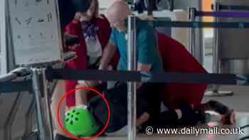 Wild moment man wearing a helmet is tackled to the ground by Virgin cabin crew in front of shocked passengers