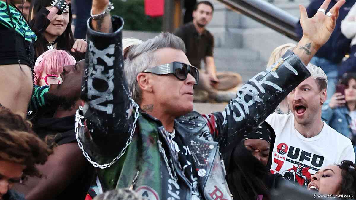 Robbie Williams, 51, rocks a biker jacket as he films dramatic scenes for his latest music video in London